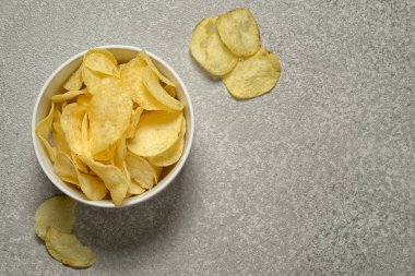 Dokulu çimento arka plan, kopya alanı ile üstten görünüm gevrek patates cipsi kase üzerinde gümüş gri.