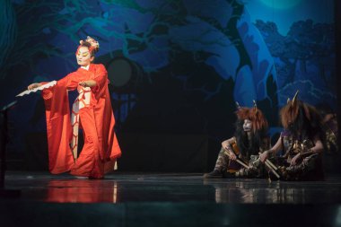 Geleneksel Japon gösterisi. Kırmızılı aktris iki mitoloji iblisine karşı hayranla dans ediyor..