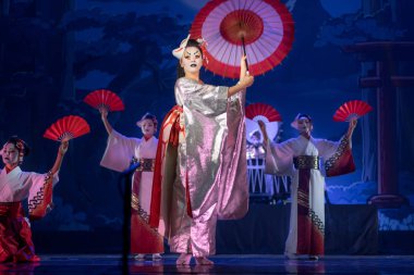 Geleneksel beyaz ve kırmızı kimonolu aktrisler ve şemsiye ve yelpazeyle dans eden tilki maskeleri..