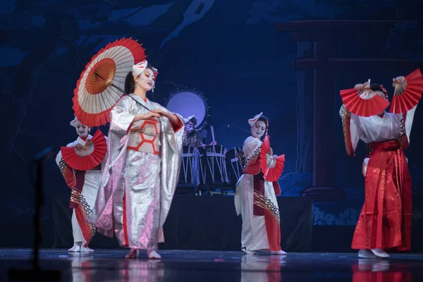 Traditional Japanese performance. Actresses in traditional white and red kimono and fox masks dancing with umbrella and fans.