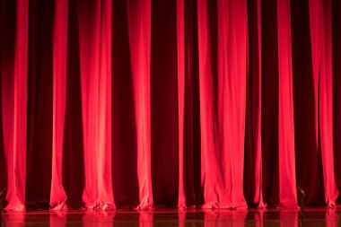 Sahne kırmızı perdesi, yer aydınlatması ve yansımaları var..