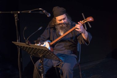 Siyahlı adam oturur ve siyah arka planda Japon ulusal shamisen telli müzik aleti çalar..