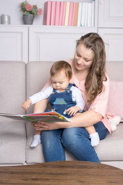 Anne ve çocuk kanepede oturmuş kitap okuyorlar.
