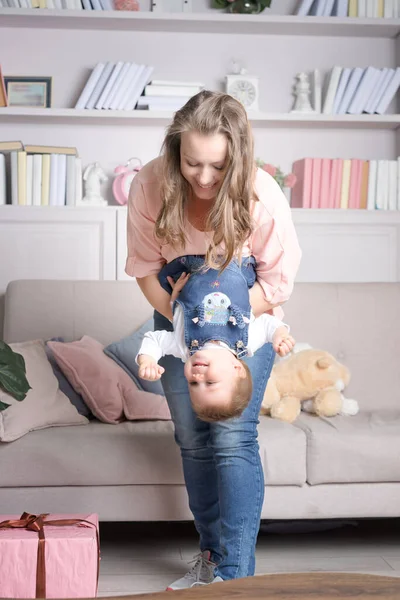 Mother holds happy baby upside down.