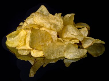 Siyah arka planda izole edilmiş siyah ayna yüzeyindeki patates cipsi yığını.