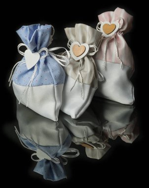 Siyah arka planda izole edilmiş siyah ayna yüzeyinde kalbi ve yayı olan üç paçavra hediye çantası. Tatil kavramı.