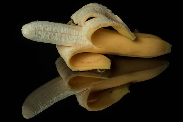 半剥皮香蕉在黑色的镜子表面上 反射在黑色的背景上 — 图库照片