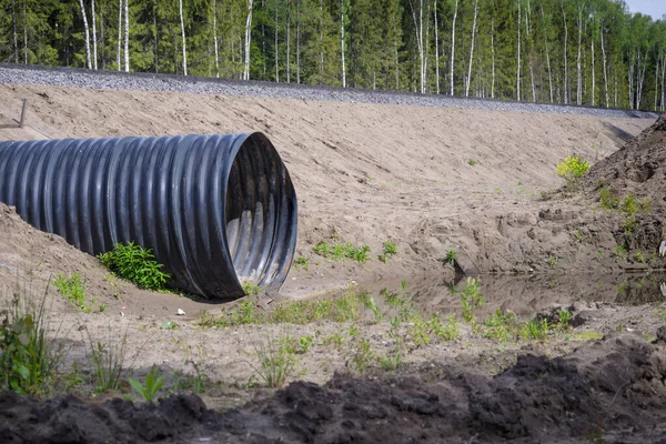New corrugated metal drainage culvert pipe installed in ditch under the road