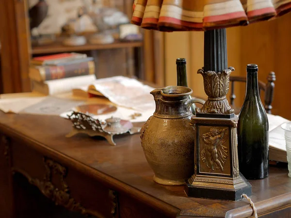 Oggetti vintage, brocca, bottiglia di vino, lampada da tavolo, calamaio, libri a — Foto Stock