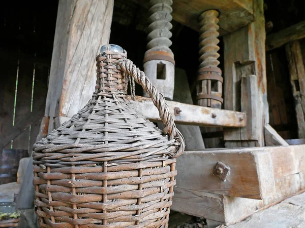 Древний деревянный винный пресс. Демиджон вина на переднем плане . — стоковое фото