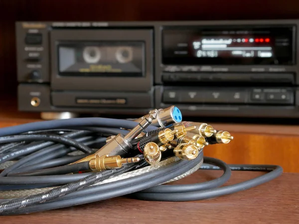 Cable accessories for musicians and listeners of quality music. Audio connectors type jack, rca, stereo, xlr. A cassette player is in the background.
