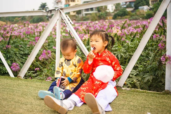 Vietnamese kids are eating cake in a roses garden — Stock Photo, Image
