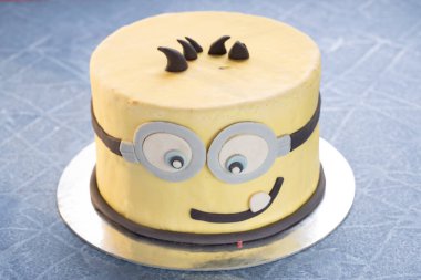 Minion çizgi film pastası çocukların doğum günü için gülümsüyor.