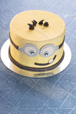 Minion çizgi film pastası çocukların doğum günü için gülümsüyor.
