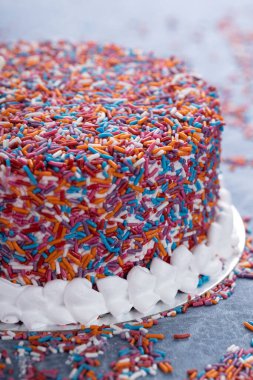 Yapay çiçekli gökkuşağı mermer pasta ve mavi bir masada çırpılmış krema kenarı.