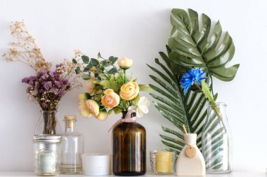 Beyaz duvardaki vazolardaki sahte çiçekler.