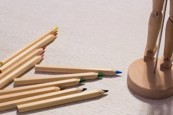 Colorful pencils on a table with puppet — Stock Photo, Image