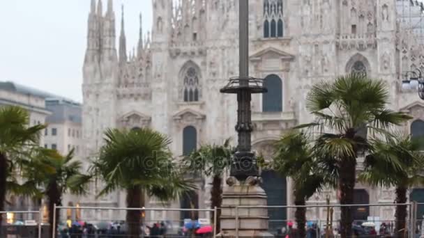 Mensen lopen in de buurt van de duomo van Milaan met palmen — Stockvideo