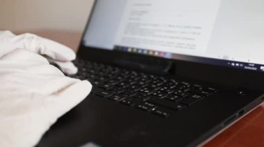 Coronavirus covid-19 sağlık durumu sırasında steril eldivenlerle bilgisayarda çalışıyor.