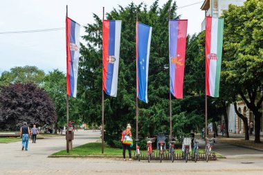 Kikinda, Sırbistan - 26 Temmuz 2019: Kikinda belediye binasının önünde bayraklar ve park edilmiş bisikletler.