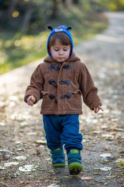 Küçük çocuk parkta bisküvi yiyor.