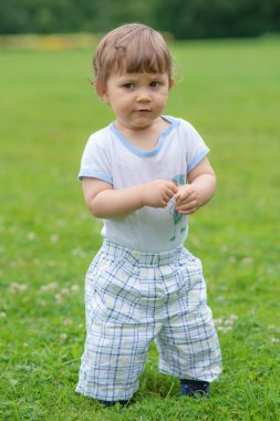 Küçük çocuk çimlere oynuyor.