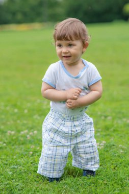 Küçük çocuk çimlere oynuyor.