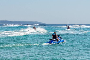 Halkidiki, Greece - September 01,2019: Possidi Beach on Halkidiki, Greece. Personal watercraft or Water motorcycle. Blue sea and a jet ski floating on Aegean sea. clipart