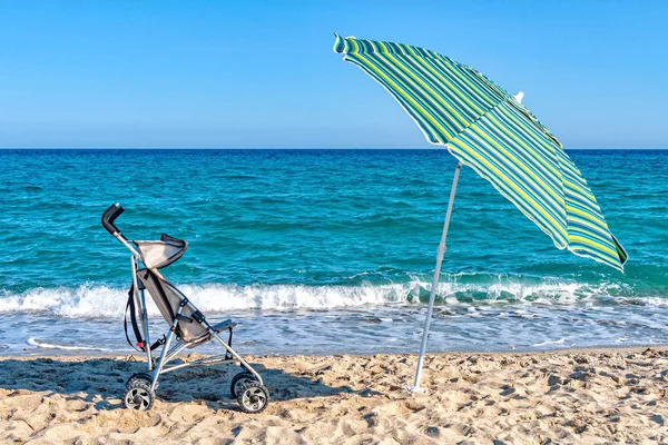 A stroller and a parasol umbrella on a sandy beach