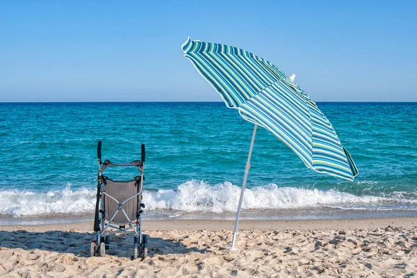 A stroller and a parasol umbrella on a sandy beach