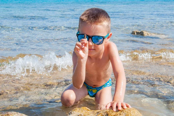 ビーチで貝殻を探している若い男の子 — ストック写真