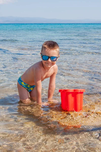 ビーチで貝殻を探している若い男の子 — ストック写真