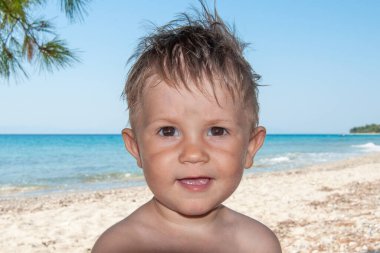 Yakın plan portre. Sevimli, mutlu erkek bebek denizin önünde.