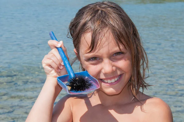 少女は海で見つけたウニを抱えている — ストック写真