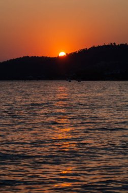Sabahın erken saatlerinde, denizin ve dağın üzerinde dramatik bir gün doğumu.