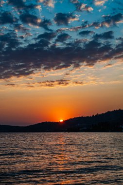 Sabahın erken saatlerinde, denizin ve dağın üzerinde dramatik bir gün doğumu.