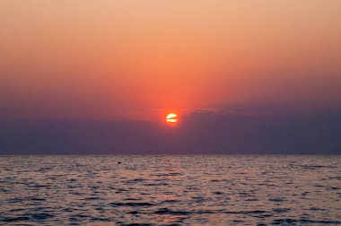 Denizin üzerinde ve bulutların arasında gün batımı