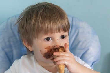 Yüzüne çikolatalı dondurma bulaşmış küçük bir çocuk. Dondurma yiyen küçük çocuk.