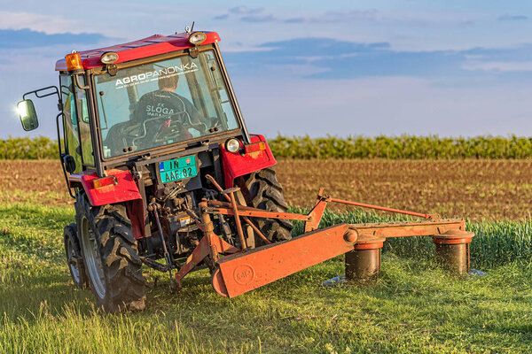 Инджия, Сербия - 07 мая 2020 года: трамвай с импедансом срезает клевер. Косилка трактора
