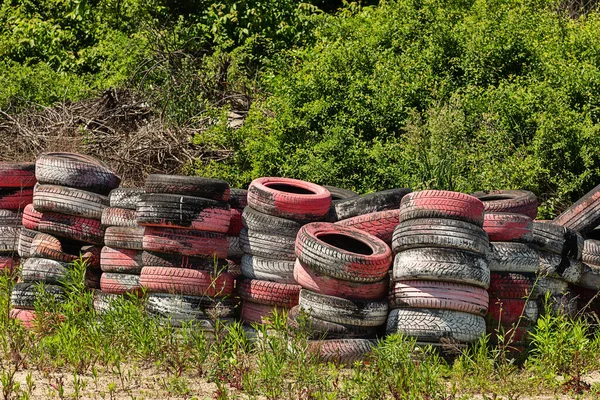 Dump of old tires of automobile wheels. Old wheel protectors. Old tyres polluting the nature. Environmental pollution.