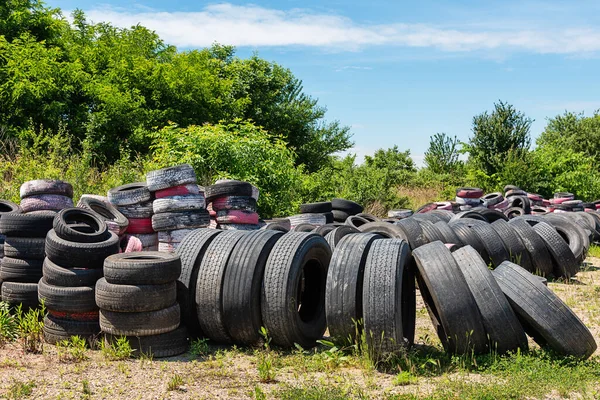 Dump of old tires of automobile wheels. Old wheel protectors. Old tyres polluting the nature. Environmental pollution.