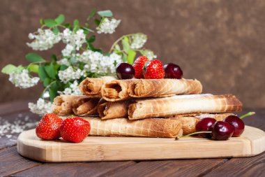 Tahta bir masada çilek ve kirazlı lezzetli waffle ruloları.