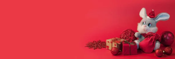 Christmas red background with fir branch, under which sits a sof — Stock Photo, Image