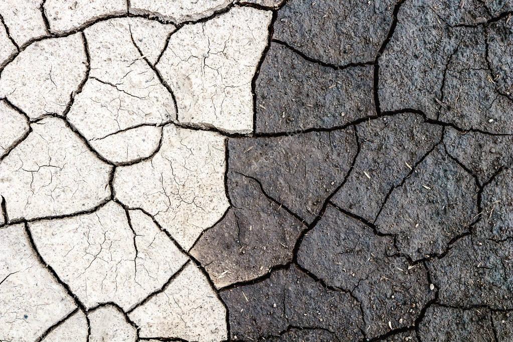 Nature background, border of dry and wet cracked mud. Concept of opposites, dark and light.