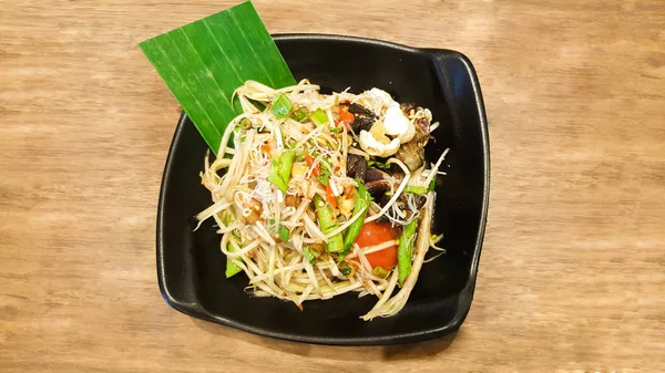 Salad pepaya dengan vermicelli dan kepiting asin di piring hitam — Stok Foto