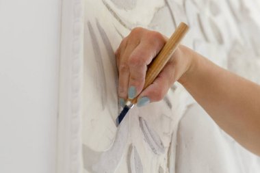 Kadın eli iş başında, bir aletle kabartma deseni oyuyor.