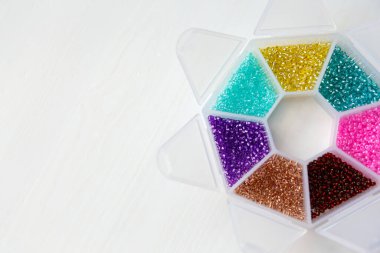 Bir kabın içinde farklı renkte boncuklar var.