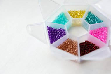 Beyaz ahşap arka planda farklı renkte boncuklar ve cam boncuklar.