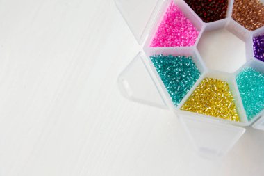 Beyaz ahşap arka planda farklı renkte boncuklar ve cam boncuklar.