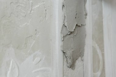 Gri beton duvarda macun harcı lekesi var.